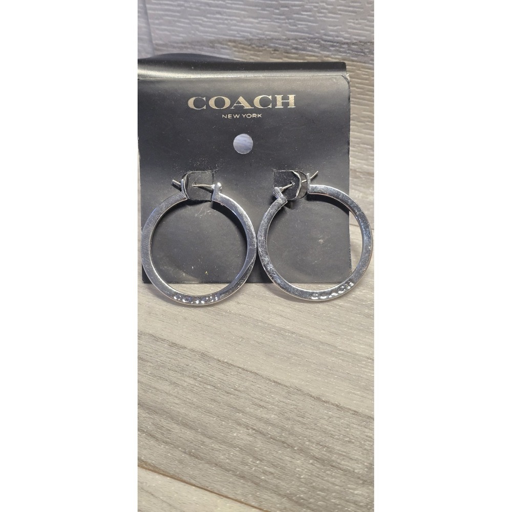 Coach Silver Hoop Earrings featuring a subtle embossed logo on the band